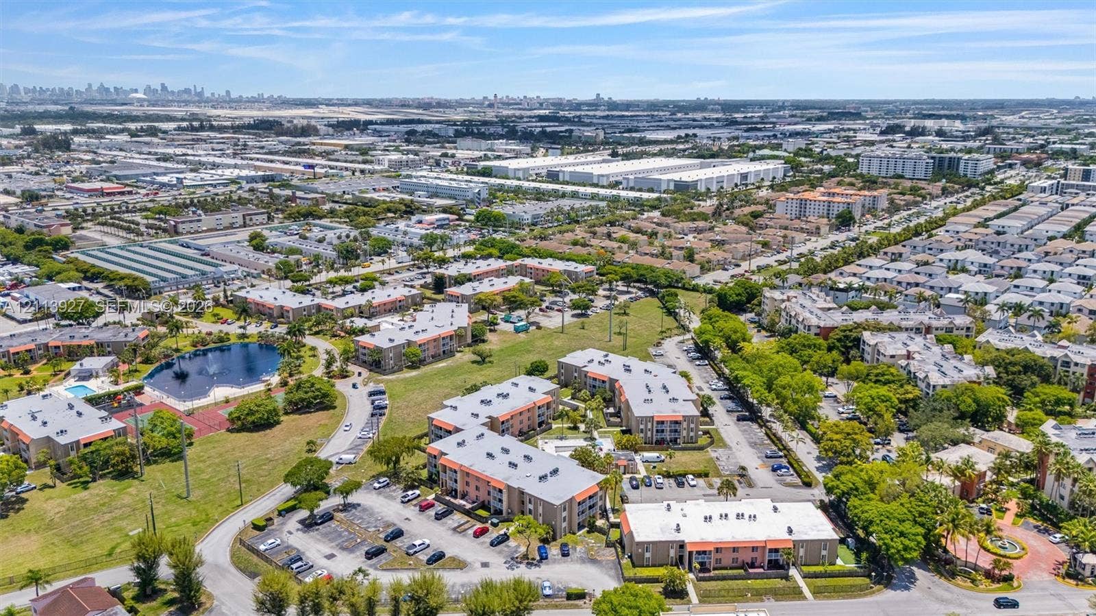4900 NW 79th Avenue, #202, Doral, Doral, FL 33166 Aerial perspective featuring multi-story residential buildings, surface parking areas, on-site pond, and landscaped green space