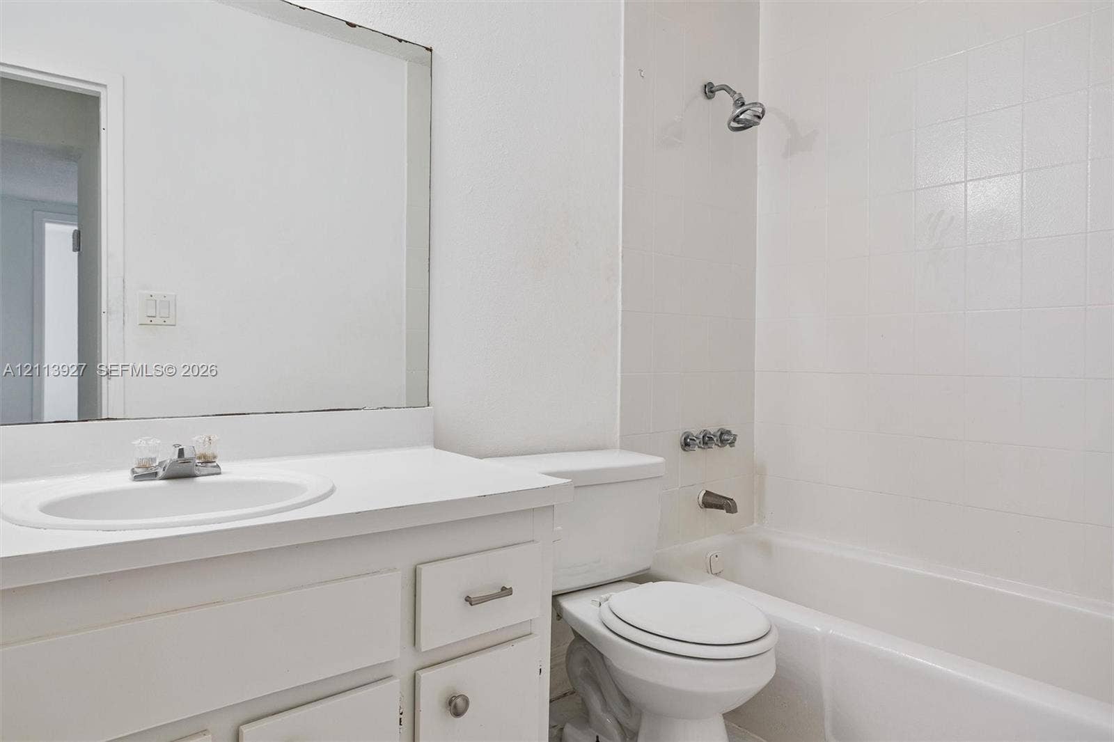 4900 NW 79th Avenue, #202, Doral, Doral, FL 33166 Bathroom featuring a white vanity cabinet with a integrated sink, a large wall-mounted mirror, a porcelain toilet, and a tiled shower-tub combination with chrome fixtures