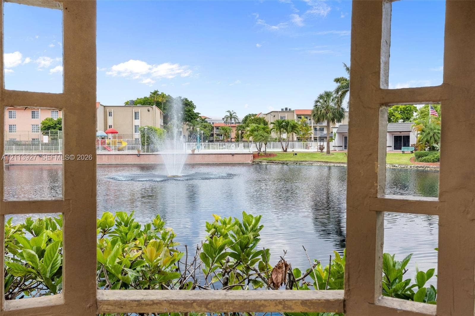 4900 NW 79th Avenue, #202, Doral, Doral, FL 33166 Stucco-framed gazebo structure overlooking a central pond featuring a built-in fountain, perimeter landscaping, and established palm trees