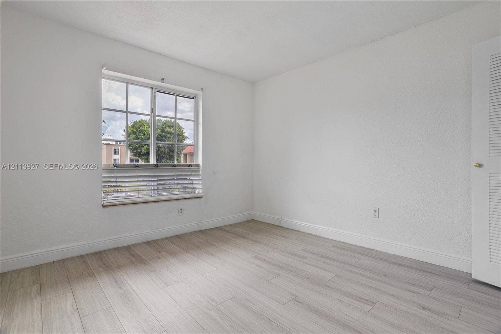 4900 NW 79th Avenue, #202, Doral, Doral, FL 33166 Neutral interior featuring light wood-finish flooring, white walls, and a multi-pane window with louvered blinds