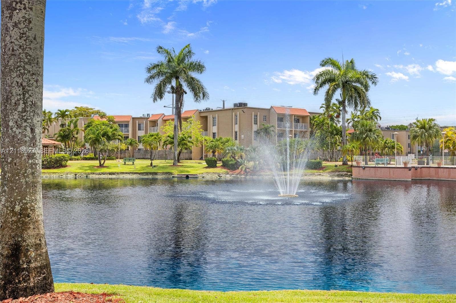 4900 NW 79th Avenue, #202, Doral, Doral, FL 33166 Waterfront grounds featuring a central fountain, manicured lawn, palm trees, and multi-story building exterior