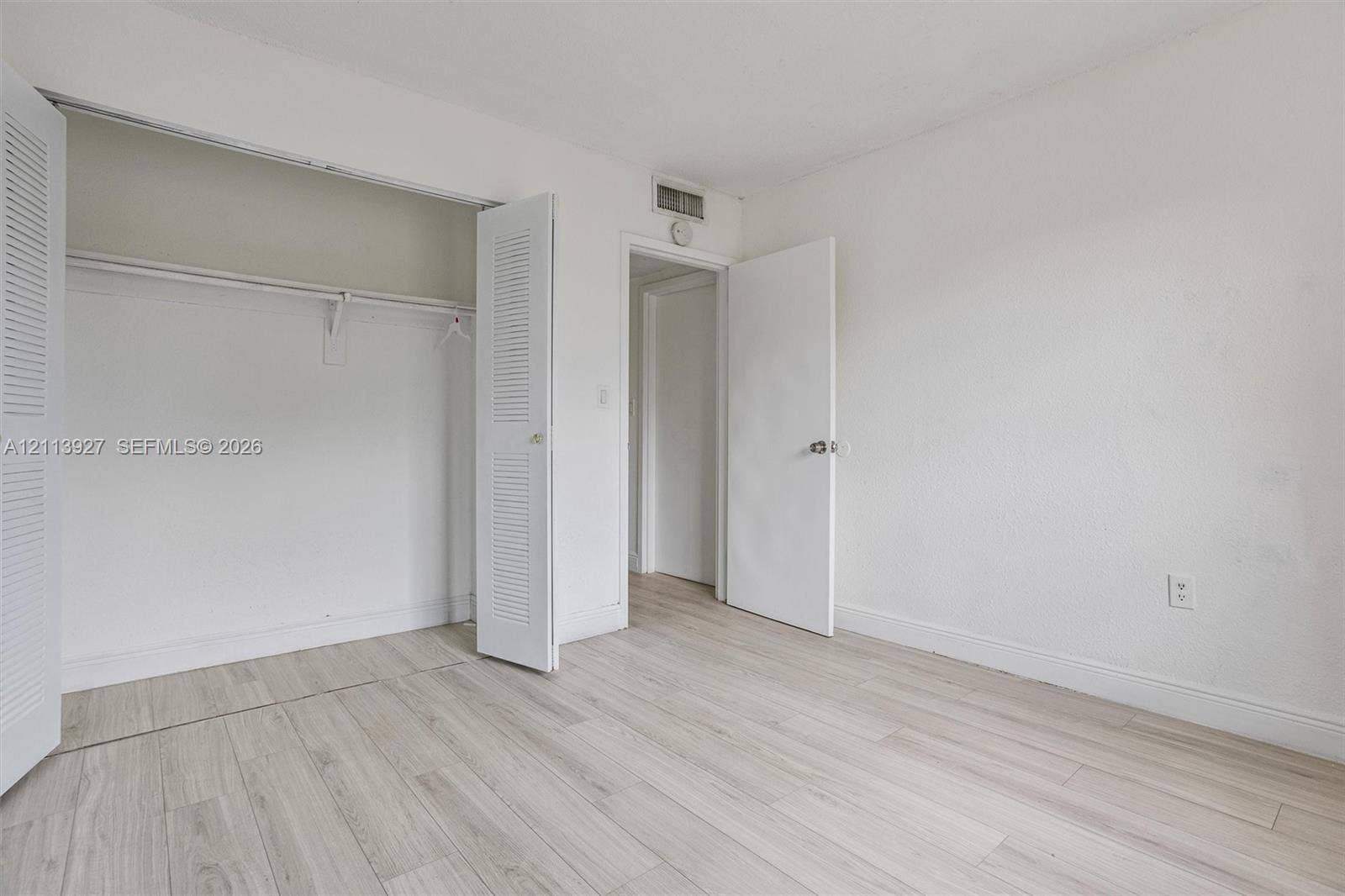 4900 NW 79th Avenue, #202, Doral, Doral, FL 33166 Room featuring wood-finish flooring, white walls, and a closet with dual louvered doors