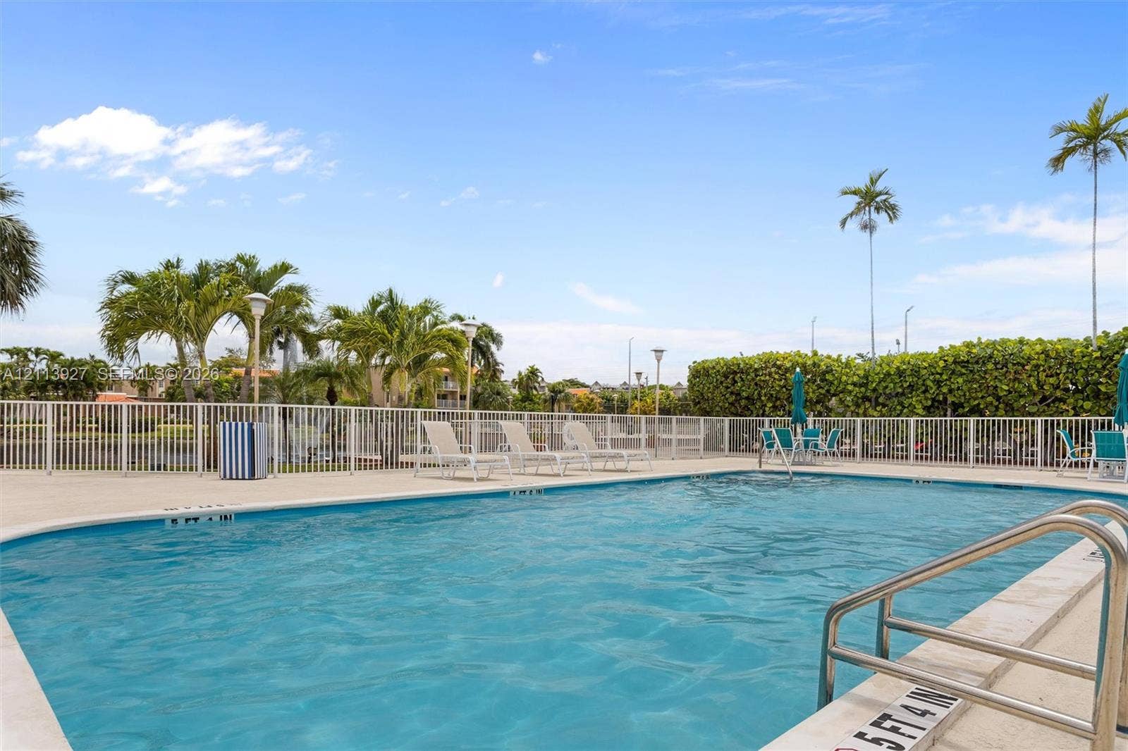 4900 NW 79th Avenue, #202, Doral, Doral, FL 33166 Outdoor swimming pool featuring a concrete deck, metal perimeter fencing, and stainless steel ladder rails