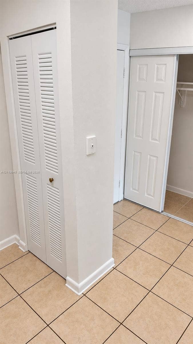 11150 SW 196th Street, #D211, Cutler Bay, Cutler Bay, FL 33157 Tile flooring, bi-fold louvered closet doors, and a sliding closet door with built-in shelving