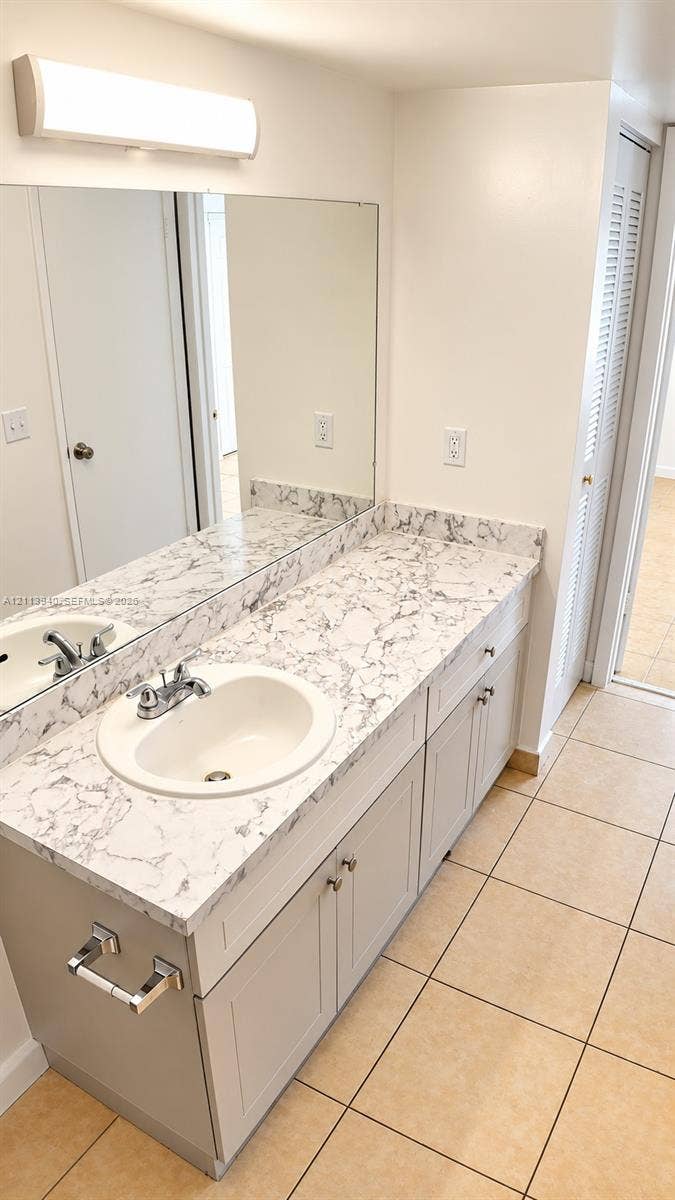 11150 SW 196th Street, #D211, Cutler Bay, Cutler Bay, FL 33157 Vanity featuring a stone-patterned countertop, dual-basin undermount sinks with metallic fixtures, light-toned cabinetry, and large-format tile flooring