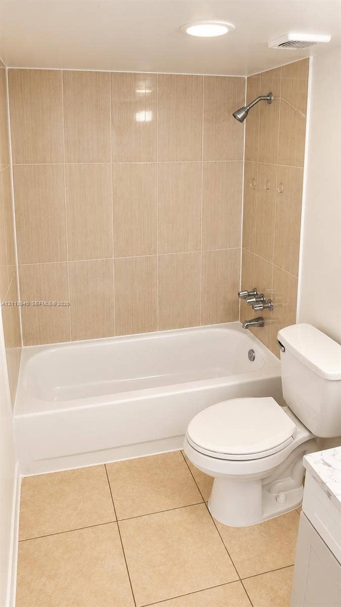 11150 SW 196th Street, #D211, Cutler Bay, Cutler Bay, FL 33157 Bathtub with a shower head, tiled wall surround, square floor tiles, and a white toilet