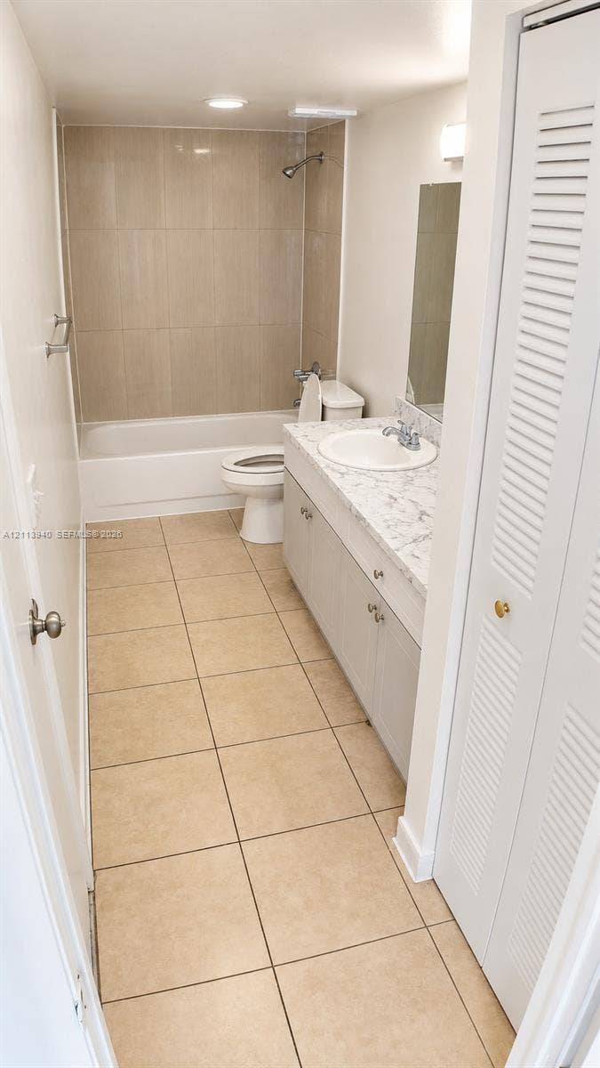 11150 SW 196th Street, #D211, Cutler Bay, Cutler Bay, FL 33157 Bathroom featuring neutral floor tiling, a vanity with a stone-finish countertop and integrated sink, a full-wall mirror, and a tub-shower combination with floor-to-ceiling surround tile