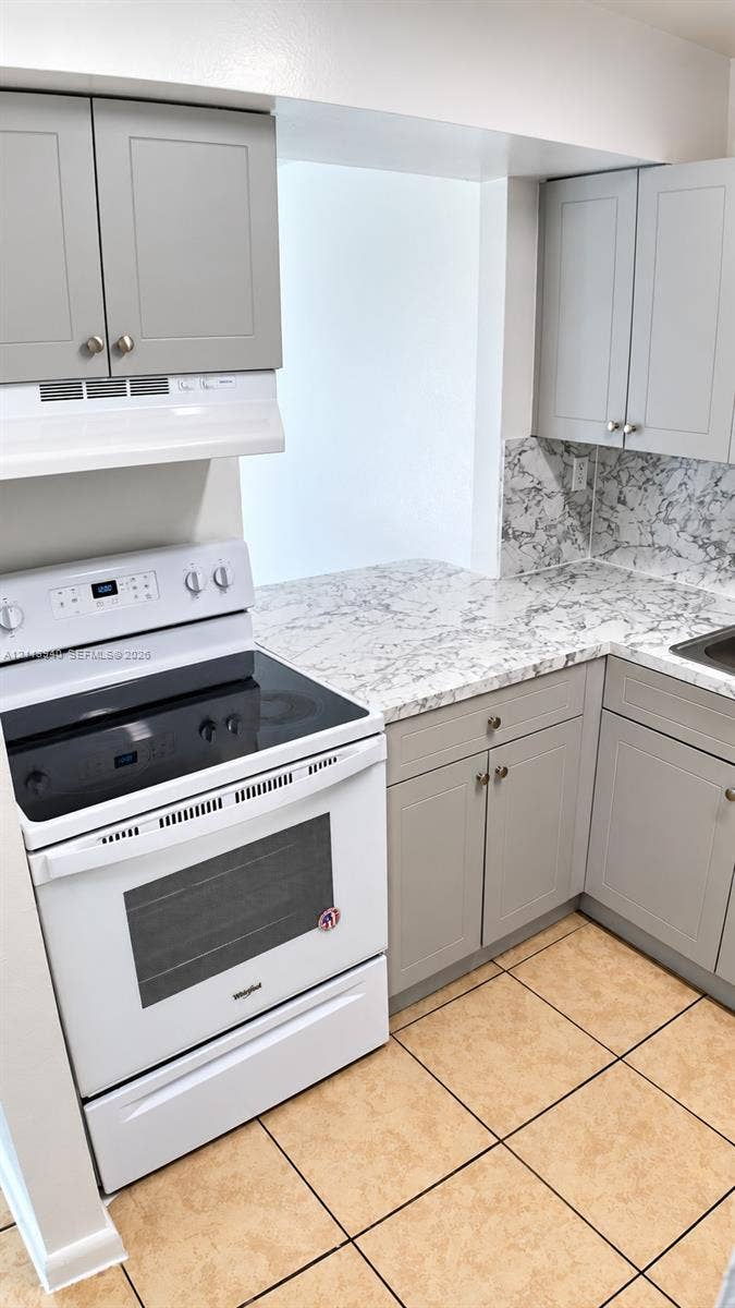 11150 SW 196th Street, #D211, Cutler Bay, Cutler Bay, FL 33157 Kitchen featuring gray shaker-style cabinetry, patterned stone-finish countertops, tiled backsplash, and a white electric range