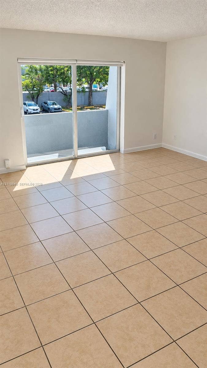11150 SW 196th Street, #D211, Cutler Bay, Cutler Bay, FL 33157 Neutral-toned ceramic tile flooring, sliding glass doors, and a private balcony with concrete wall enclosure