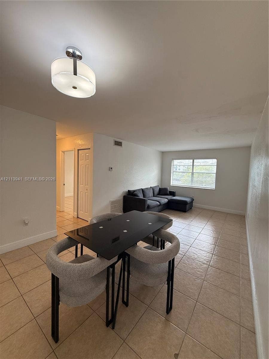 17255 SW 95th Avenue, #457, Palmetto Bay, Palmetto Bay, FL 33157 Open-concept room featuring light-toned tile flooring, a drum-style ceiling light fixture, and a large multi-pane window