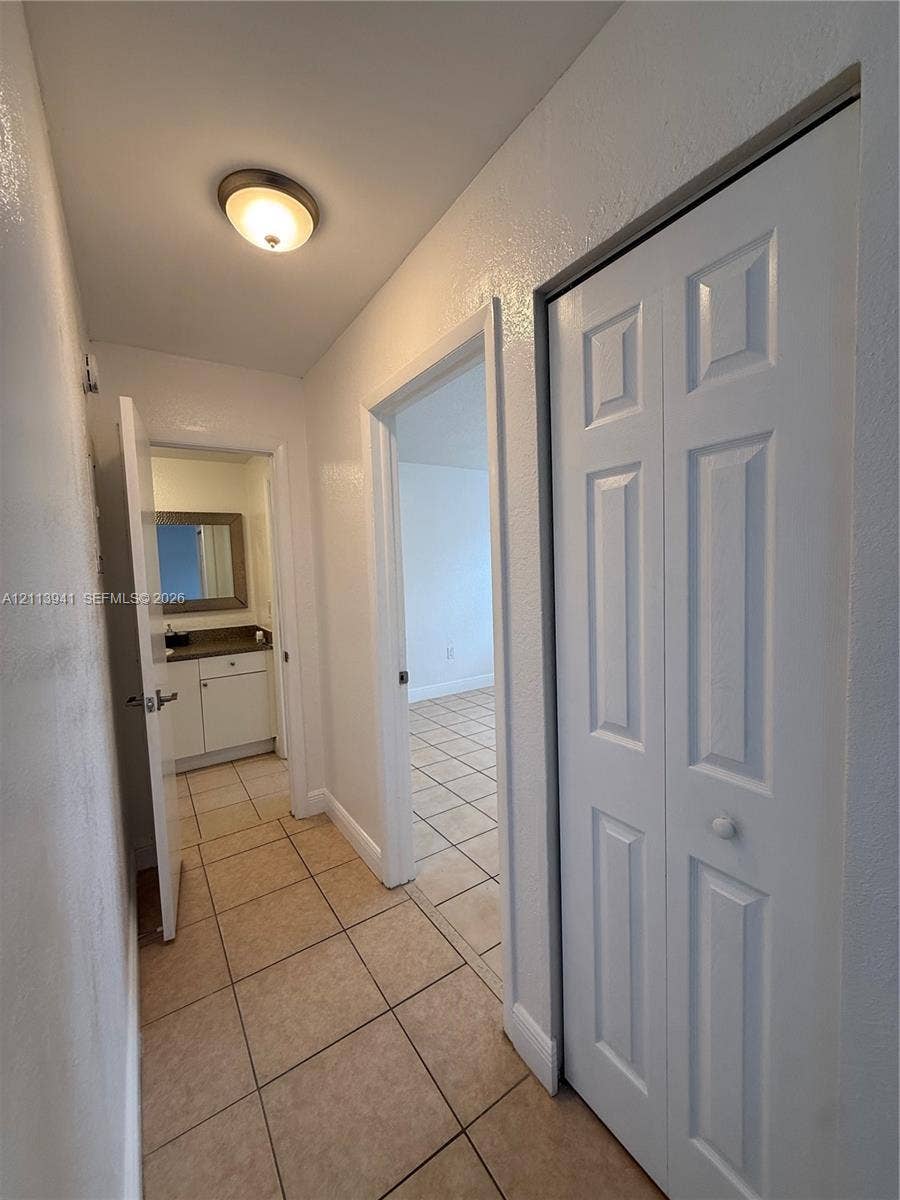 17255 SW 95th Avenue, #457, Palmetto Bay, Palmetto Bay, FL 33157 Hallway featuring neutral tile flooring, a six-panel bifold closet door, and a flush-mount dome light fixture
