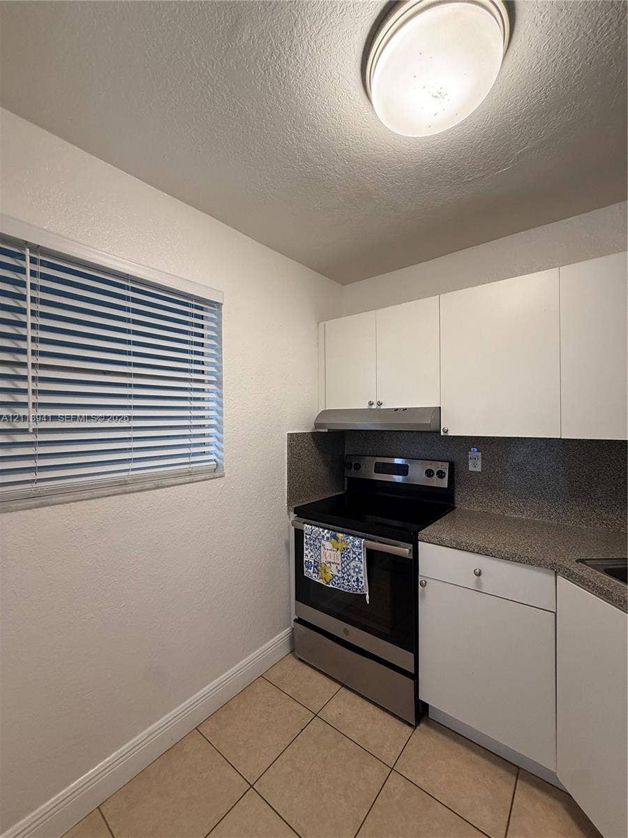 17255 SW 95th Avenue, #457, Palmetto Bay, Palmetto Bay, FL 33157 Kitchen featuring white flat-panel cabinetry, stone-finish countertops, stainless steel range, matching range hood, and tile flooring