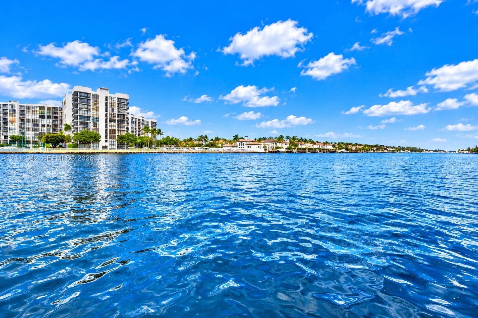 2710 S Ocean Drive, #401, Hollywood, FL 33019 Direct waterfront setting featuring expansive water frontage, multi-story coastal architecture, and mature palm tree landscaping