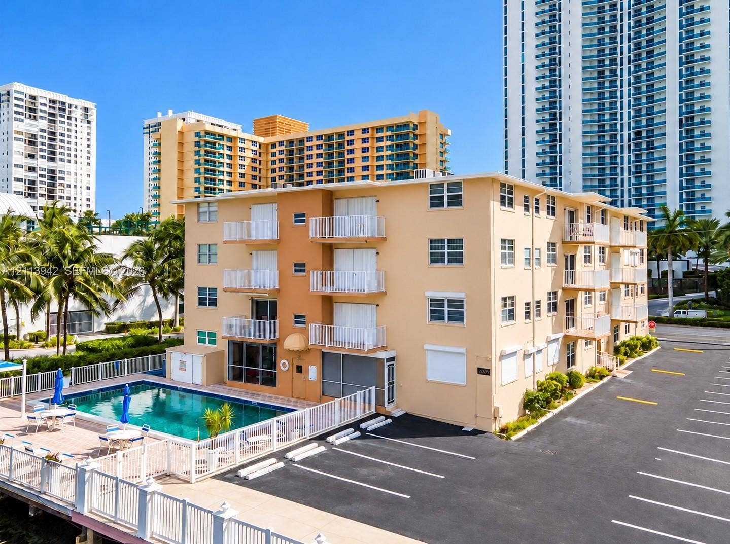 2710 S Ocean Drive, #401, Hollywood, FL 33019 Multi-story residential building featuring private exterior balconies, an outdoor swimming pool, a perimeter fence, and surface parking