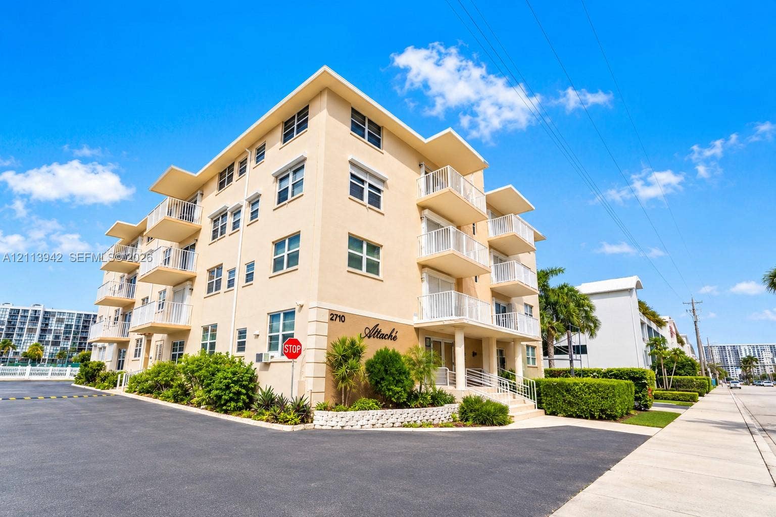 2710 S Ocean Drive, #401, Hollywood, FL 33019 Multi-story building exterior featuring smooth stucco finish, tiered private balconies with metal railings, and integrated ground-level landscaping
