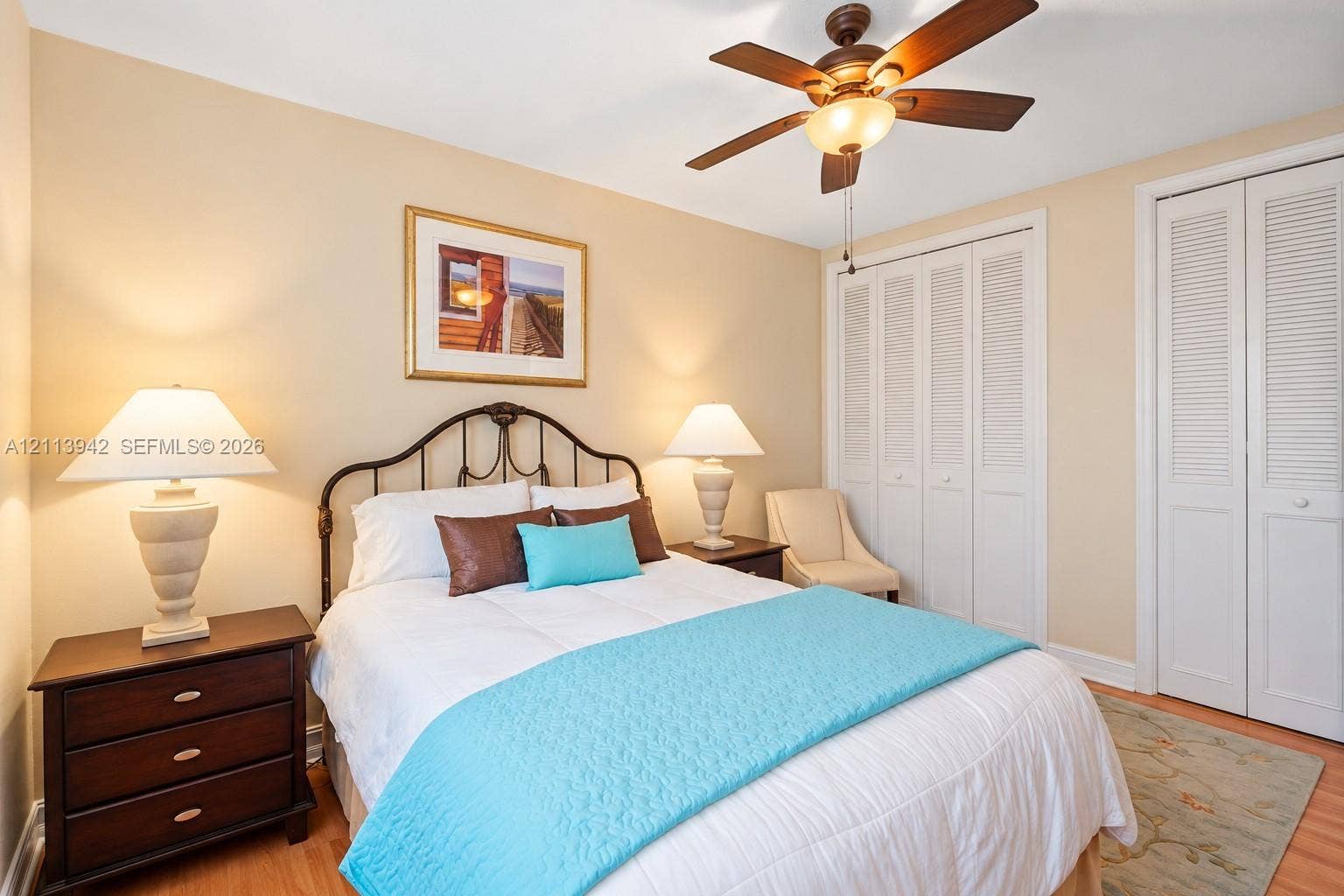 2710 S Ocean Drive, #401, Hollywood, FL 33019 Neutral-toned interior featuring wood-finish flooring, a ceiling fan with integrated light fixture, and dual white louvered-panel closets