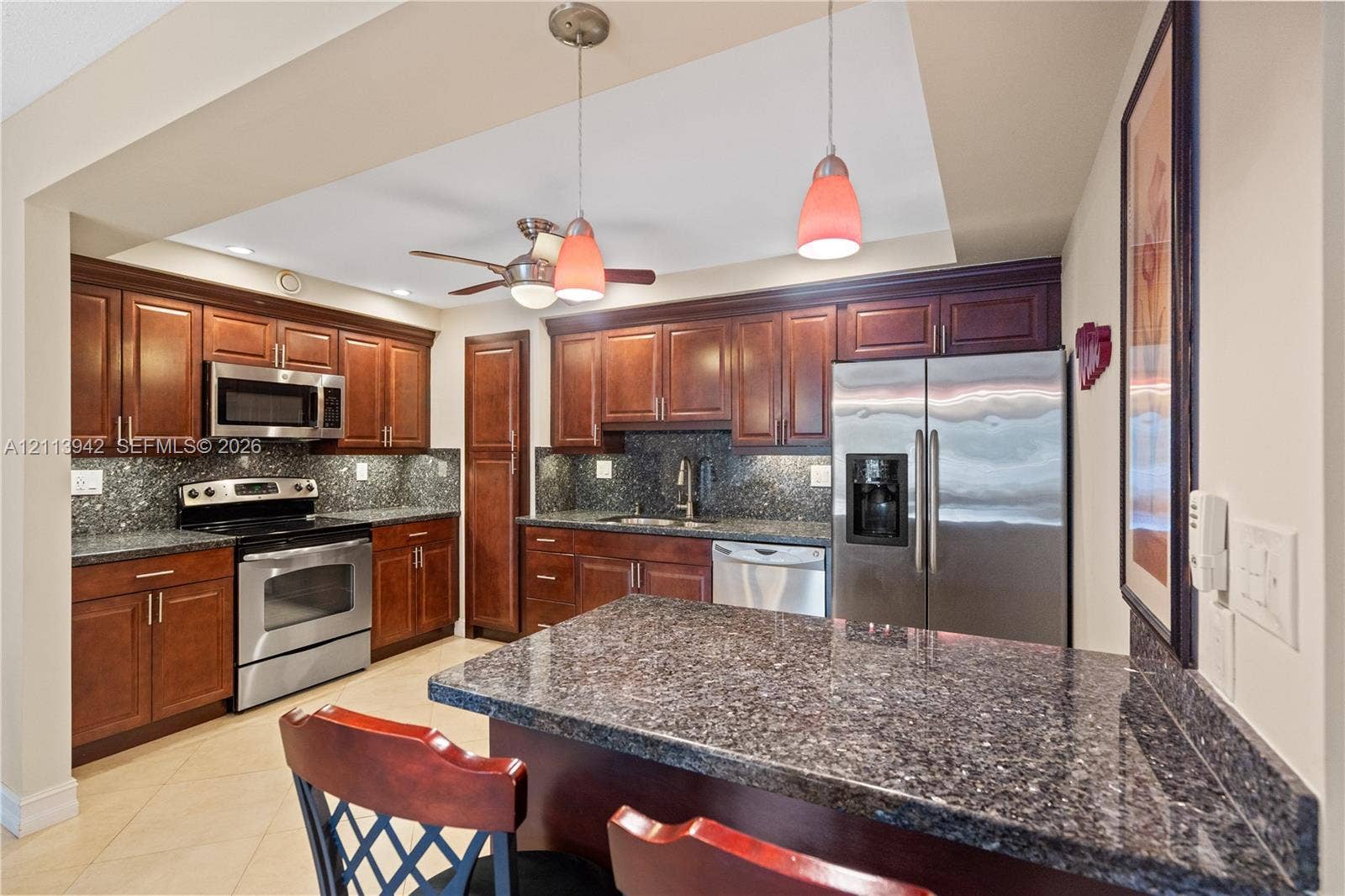 2710 S Ocean Drive, #401, Hollywood, FL 33019 Kitchen featuring dark-toned cabinetry, stone countertops, stainless steel appliances, a center island with bar seating, and pendant lighting