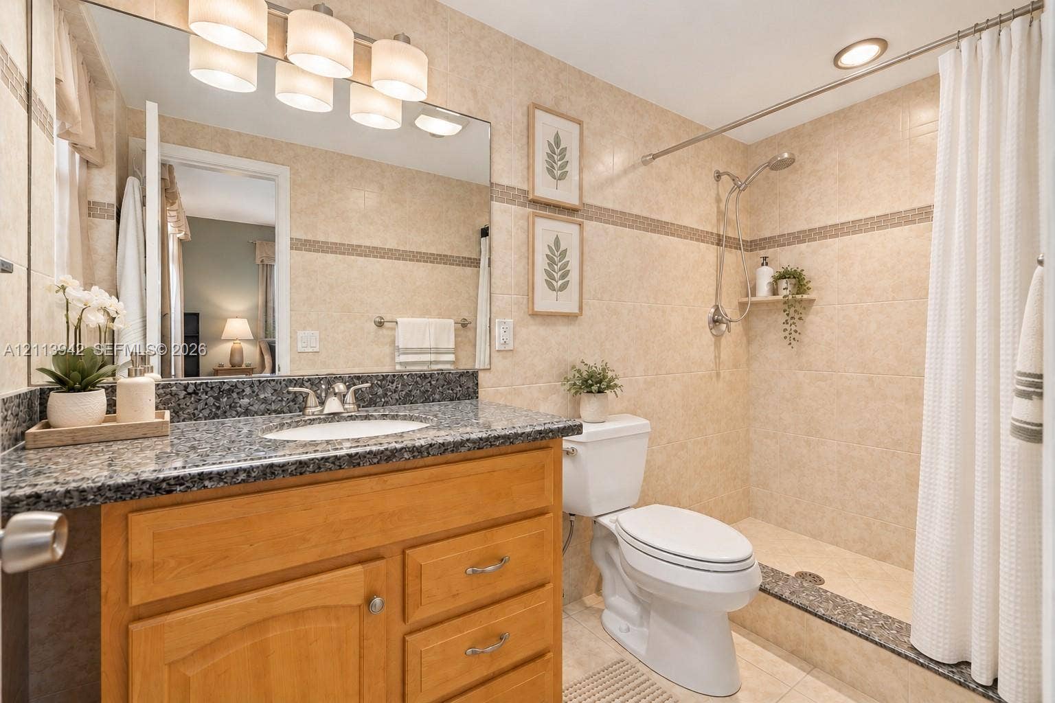 2710 S Ocean Drive, #401, Hollywood, FL 33019 Bathroom featuring a wood-finish vanity with a stone-top counter, undermount sink, multi-light fixture, and a tiled shower stall with a built-in shelf