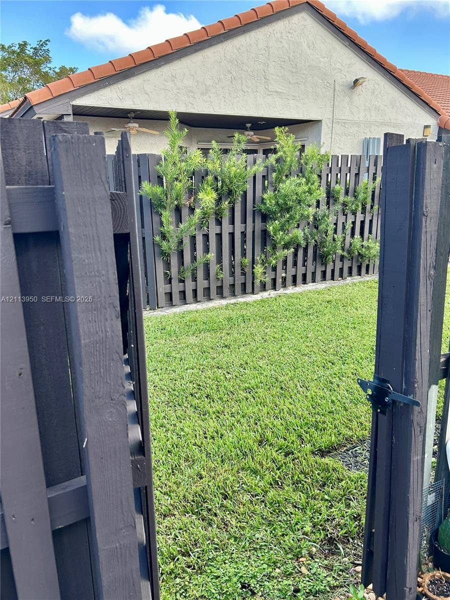 Private backyard featuring a manicured lawn, full-height perimeter wood fencing, and a covered patio area