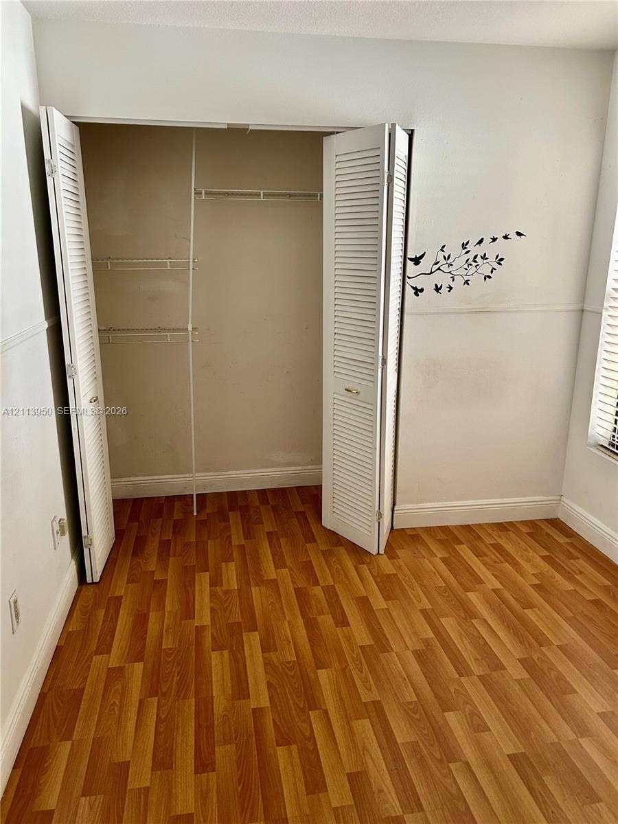 Wood-finish flooring, white louvered closet doors, and interior wire shelving