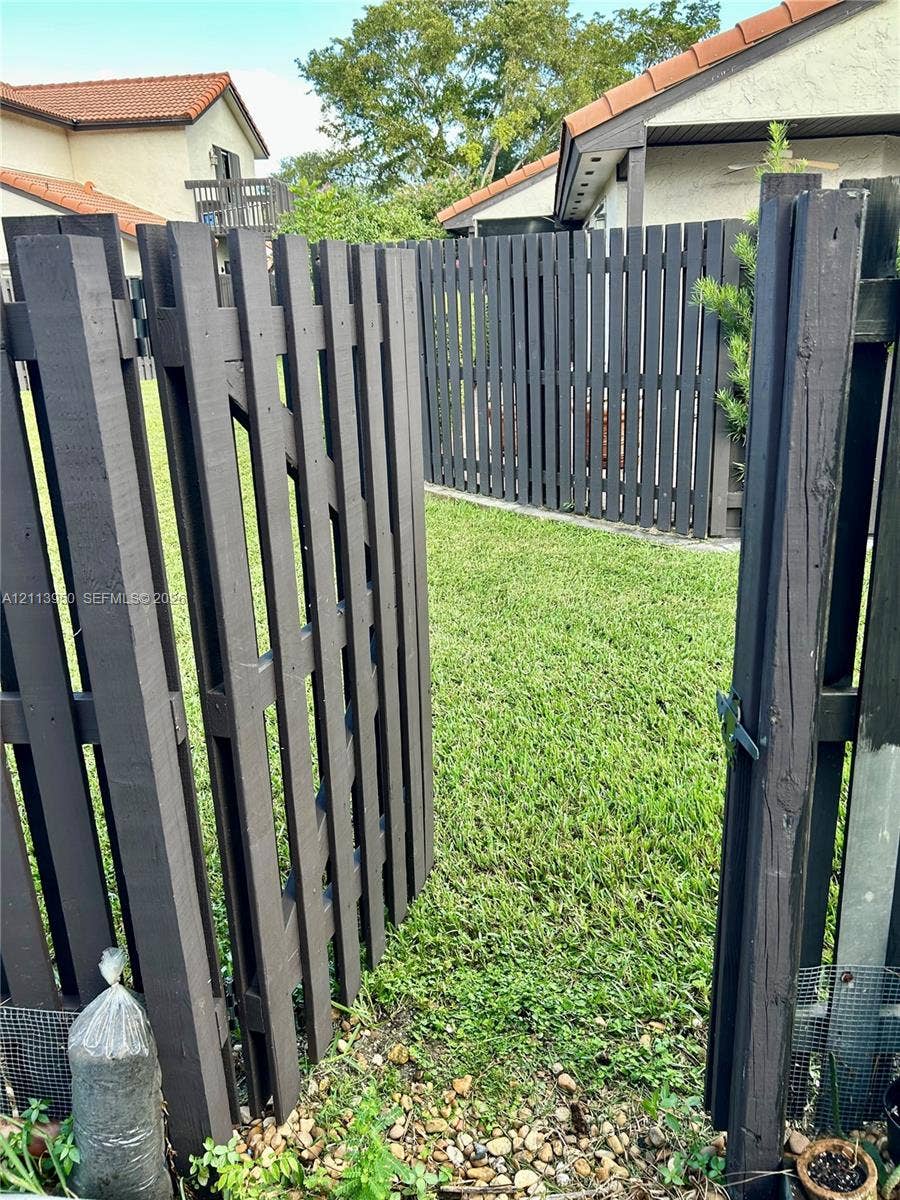 Enclosed yard featuring a dark-finish wood fence, gated entry, and manicured lawn