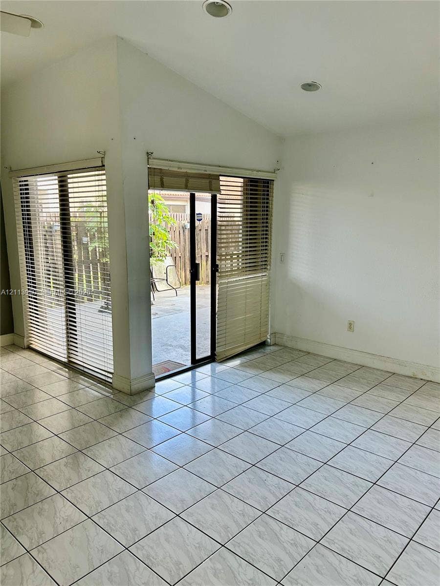Ceramic tile flooring, vaulted ceiling with recessed lighting, and corner sliding glass doors