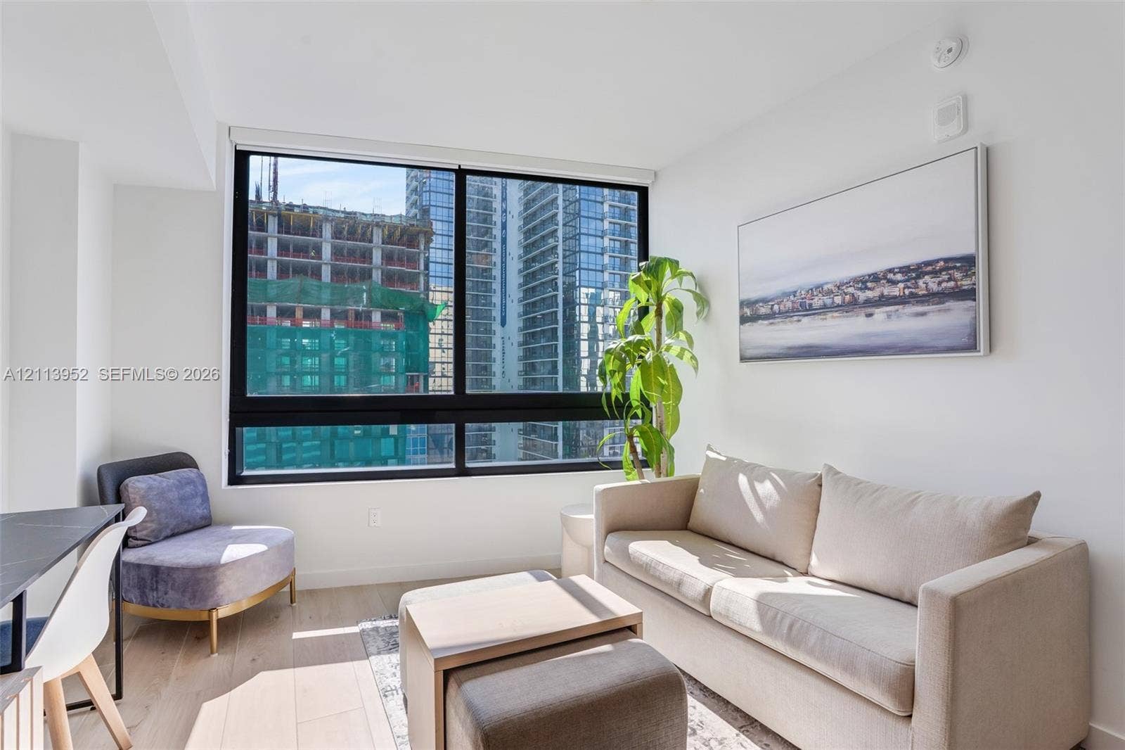 Floor-to-ceiling black-framed windows, wood-finish flooring, and crisp neutral wall finish