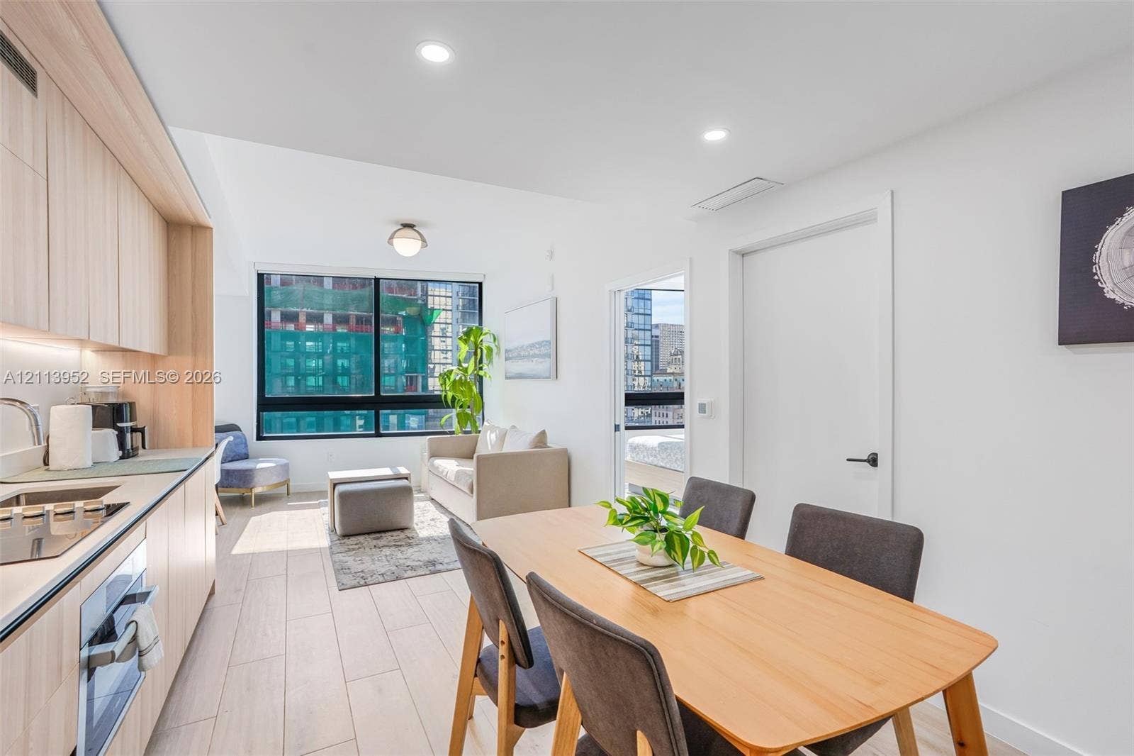 Contemporary kitchen featuring light-toned cabinetry, built-in electric cooktop, and flush-mount integrated lighting