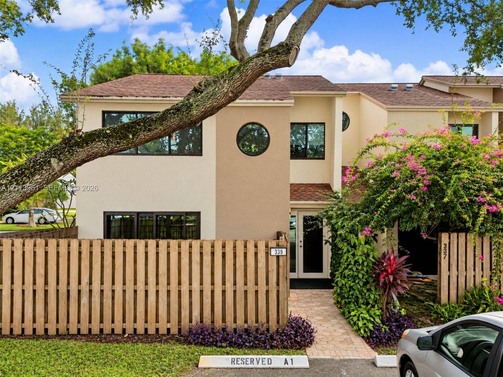 339 City View Drive, #339, Fort Lauderdale, Fort Lauderdale, FL 33311 Exterior facade featuring a two-story stucco finish, prominent circular accent window, shingle roofing, and a private wooden privacy fence