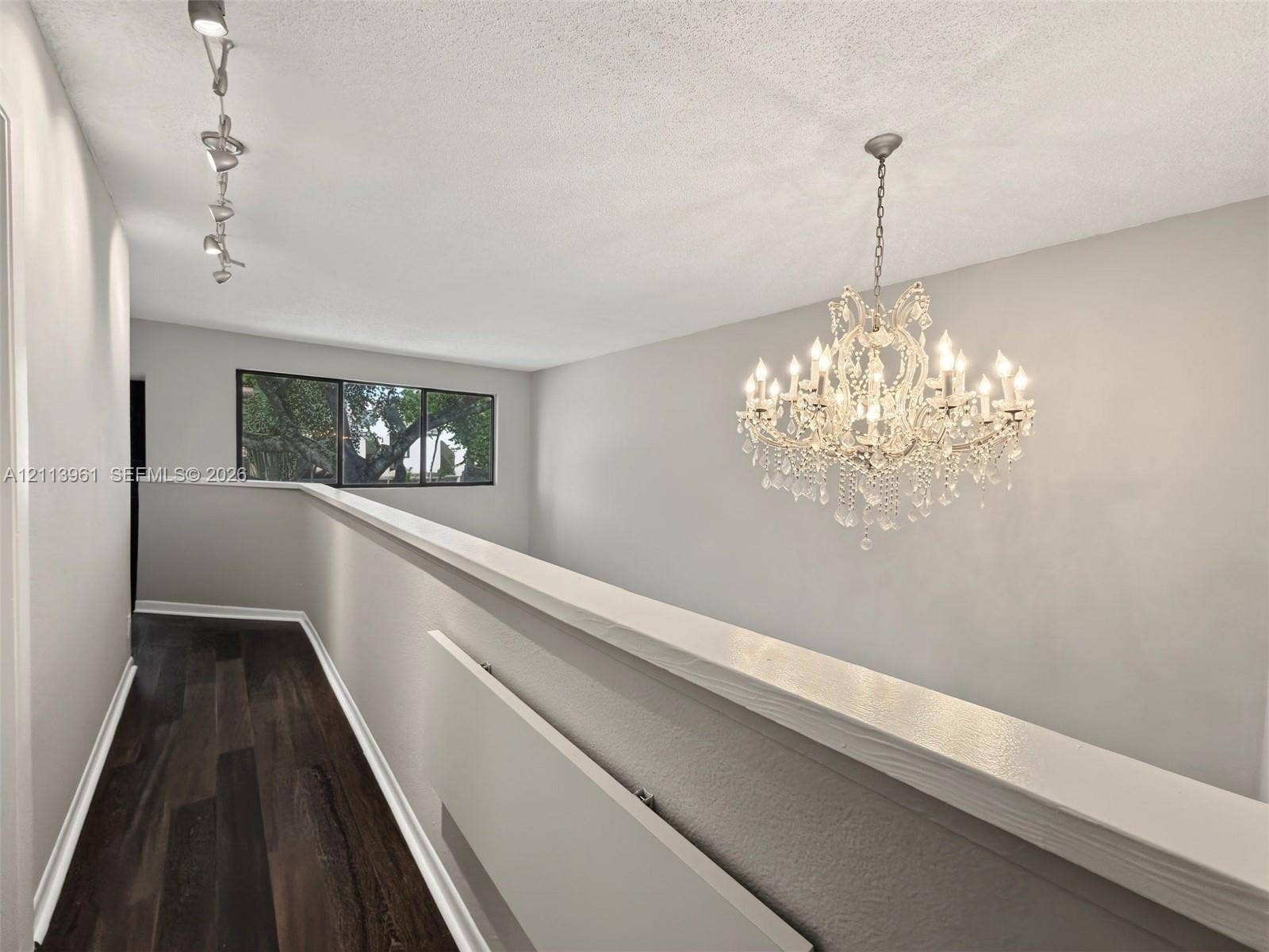339 City View Drive, #339, Fort Lauderdale, Fort Lauderdale, FL 33311 Wood-finish flooring, ornate crystal chandelier, track lighting, and window with natural greenery exposure