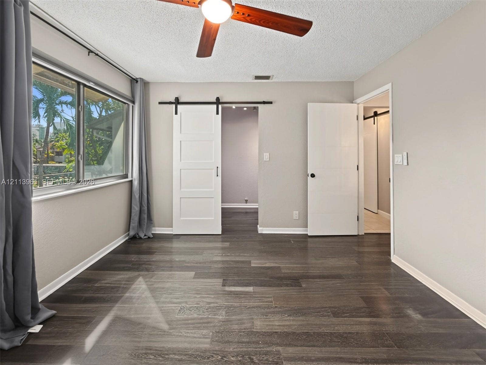 339 City View Drive, #339, Fort Lauderdale, Fort Lauderdale, FL 33311 Wood-finish flooring, white four-panel sliding barn door, ceiling fan, and multi-pane horizontal window