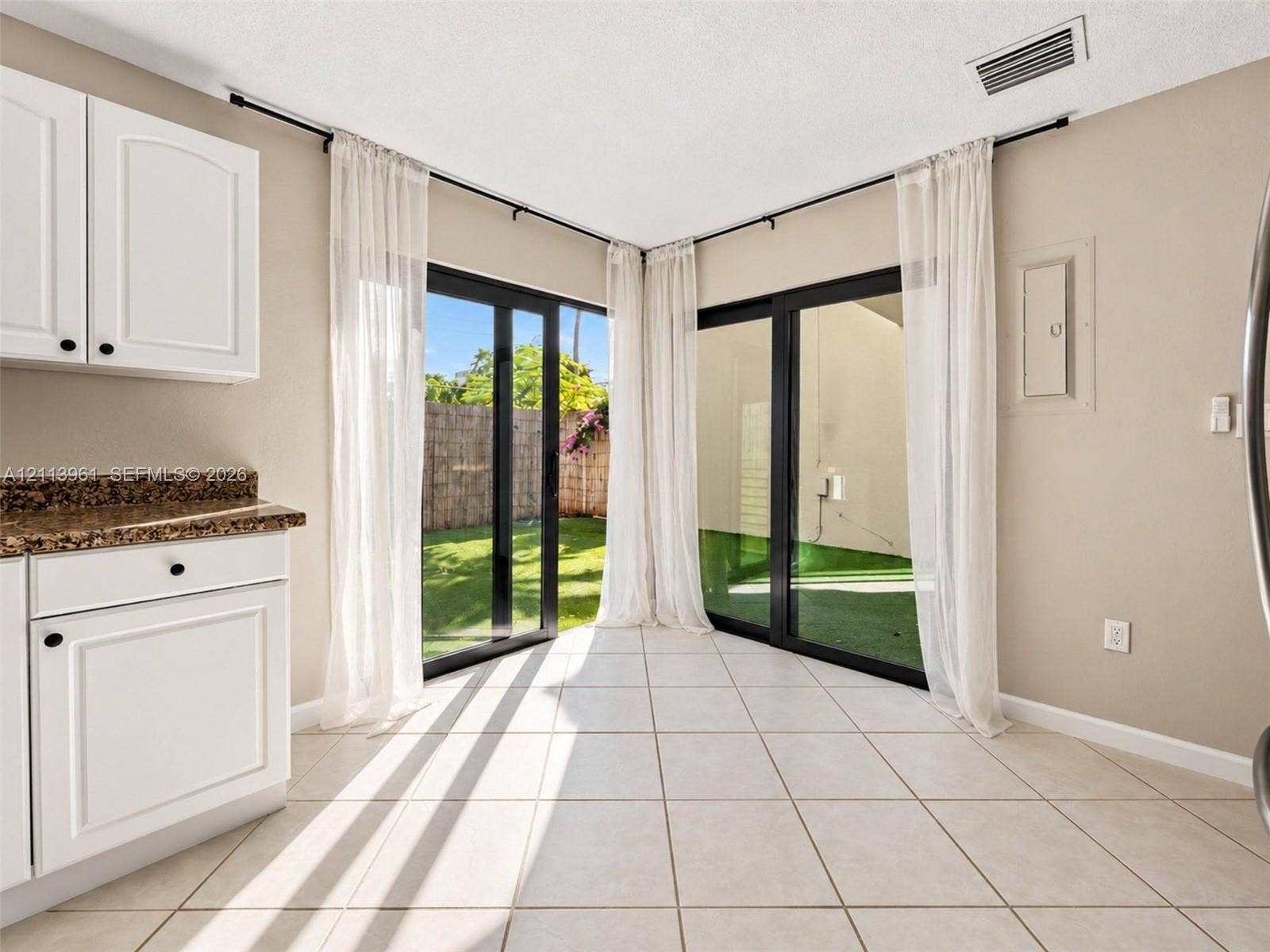 339 City View Drive, #339, Fort Lauderdale, Fort Lauderdale, FL 33311 Dual sliding glass doors, white cabinetry, stone-finish countertops, and light-toned tile flooring