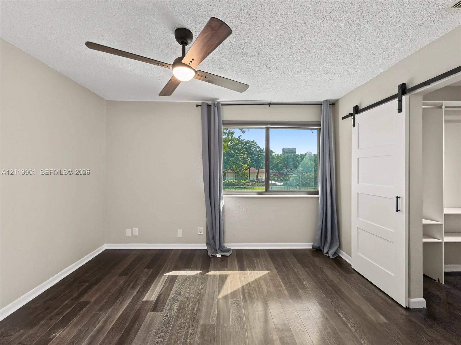 339 City View Drive, #339, Fort Lauderdale, Fort Lauderdale, FL 33311 Wood-finish flooring, white sliding barn door, integrated shelving, modern ceiling fan with light fixture, and single-pane window