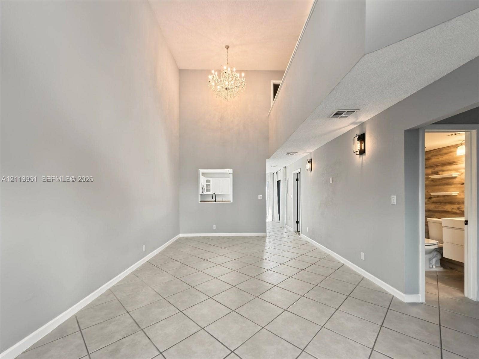 339 City View Drive, #339, Fort Lauderdale, Fort Lauderdale, FL 33311 Vaulted ceilings, large-format tile flooring laid on the diagonal, multi-tiered crystal chandelier, recessed wall niche, and matching matte black wall-mounted fixtures