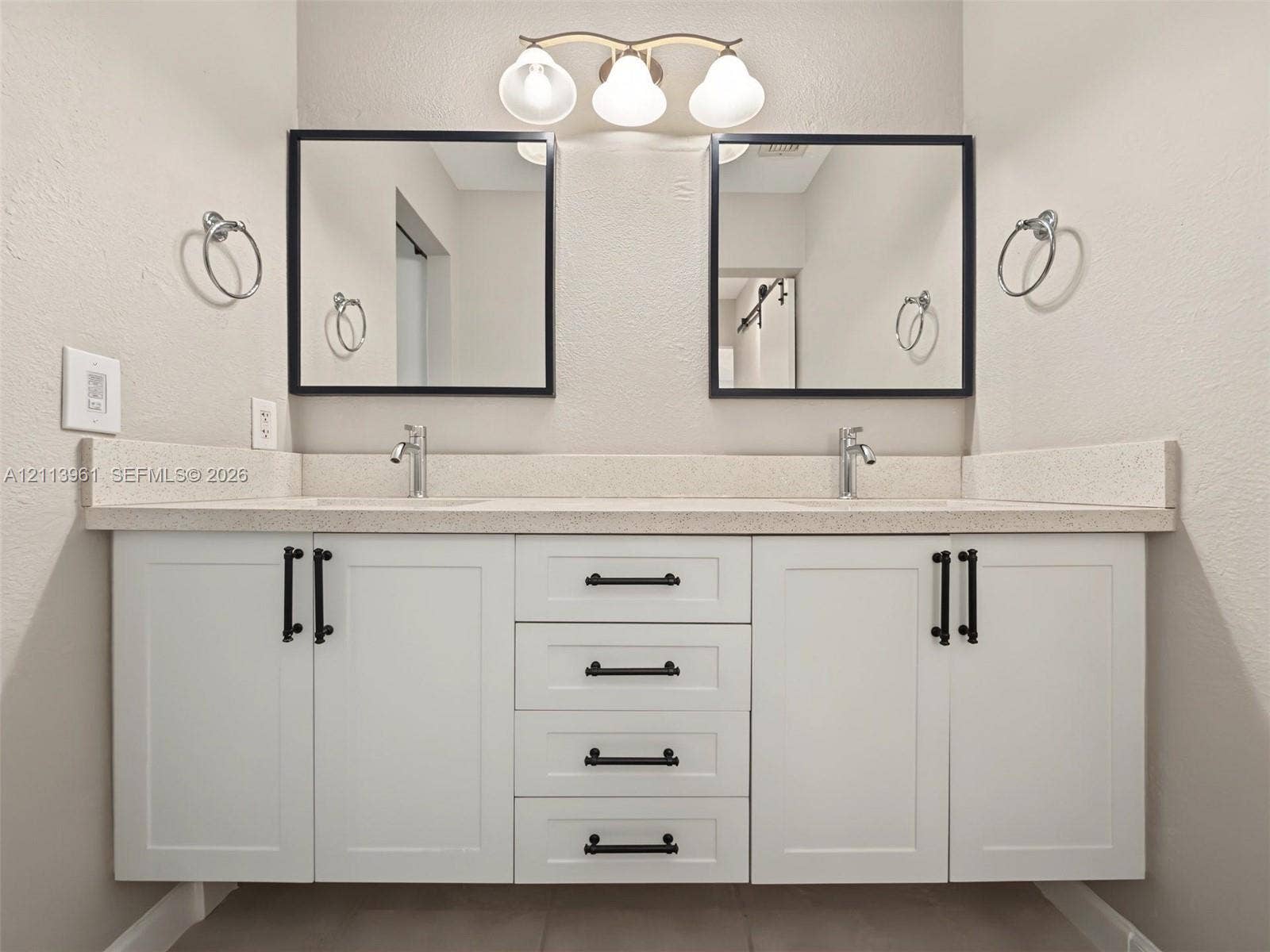 339 City View Drive, #339, Fort Lauderdale, Fort Lauderdale, FL 33311 Dual-sink vanity featuring white cabinetry, solid surface countertop, matte black hardware, square mirrors with black frames, and a three-bulb light fixture