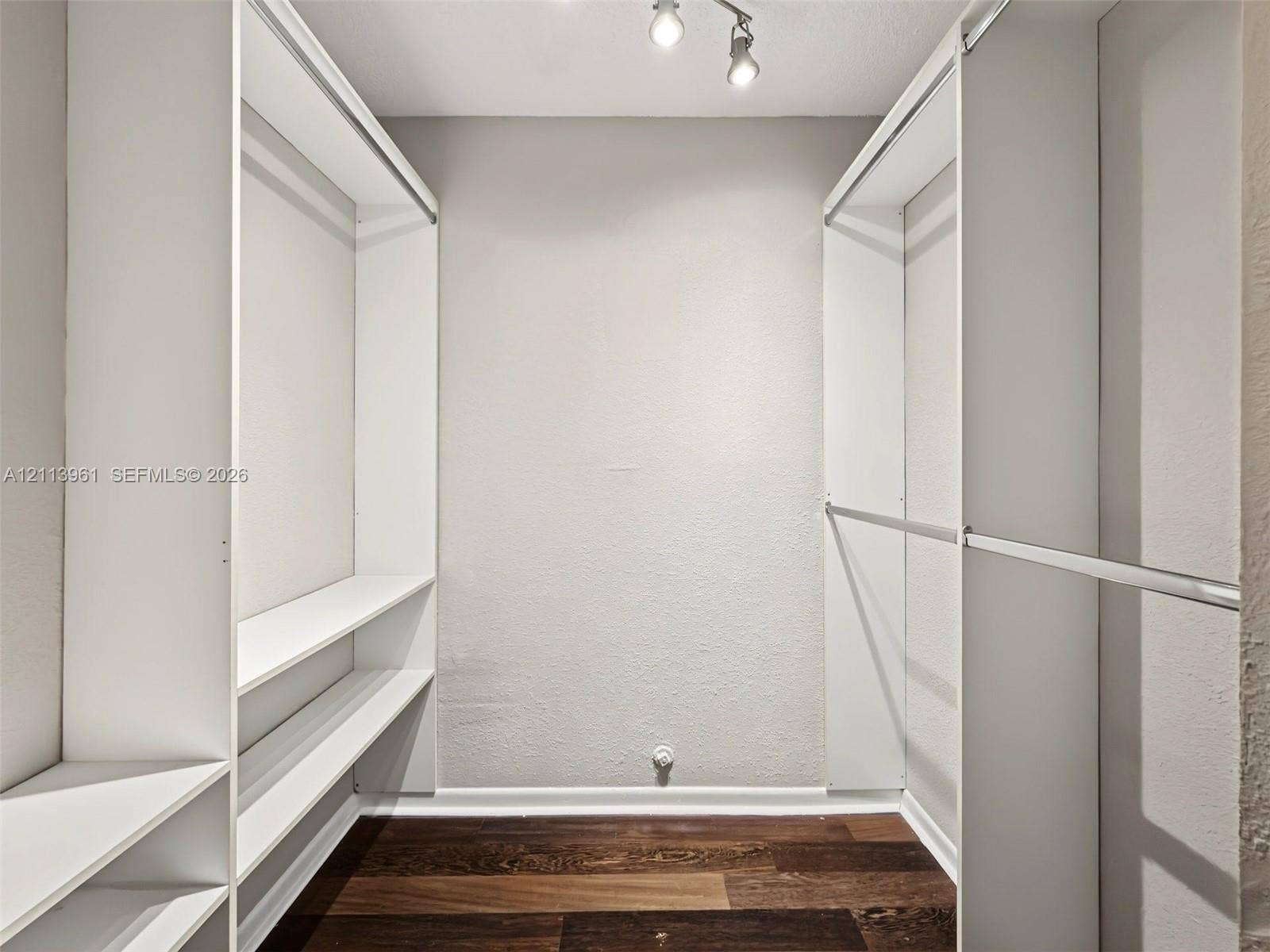 339 City View Drive, #339, Fort Lauderdale, Fort Lauderdale, FL 33311 Walk-in closet featuring white built-in shelving, integrated garment rods, wood-finish flooring, and multi-directional ceiling-mounted lighting