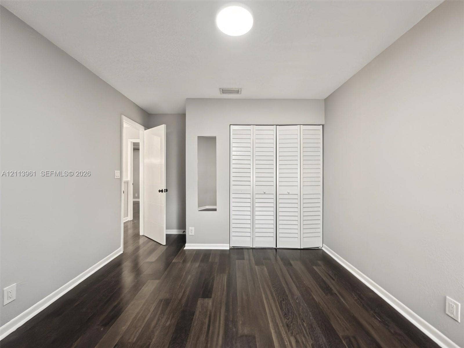 339 City View Drive, #339, Fort Lauderdale, Fort Lauderdale, FL 33311 Room featuring wood-finish flooring, white louvered closet doors, and a neutral wall palette