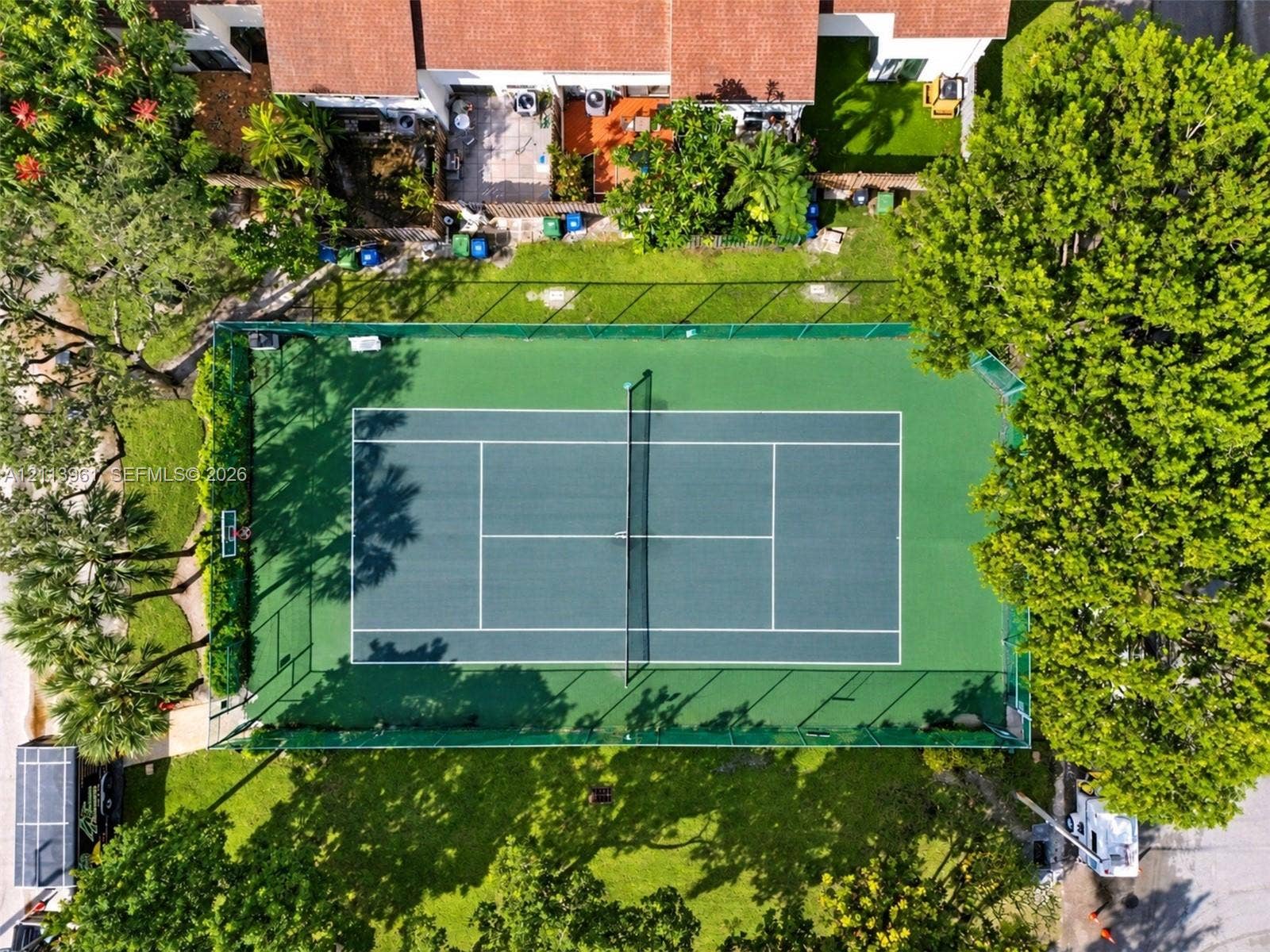339 City View Drive, #339, Fort Lauderdale, Fort Lauderdale, FL 33311 Full-size tennis court featuring a perimeter fence, basketball hoop, and surrounding manicured lawn with mature trees