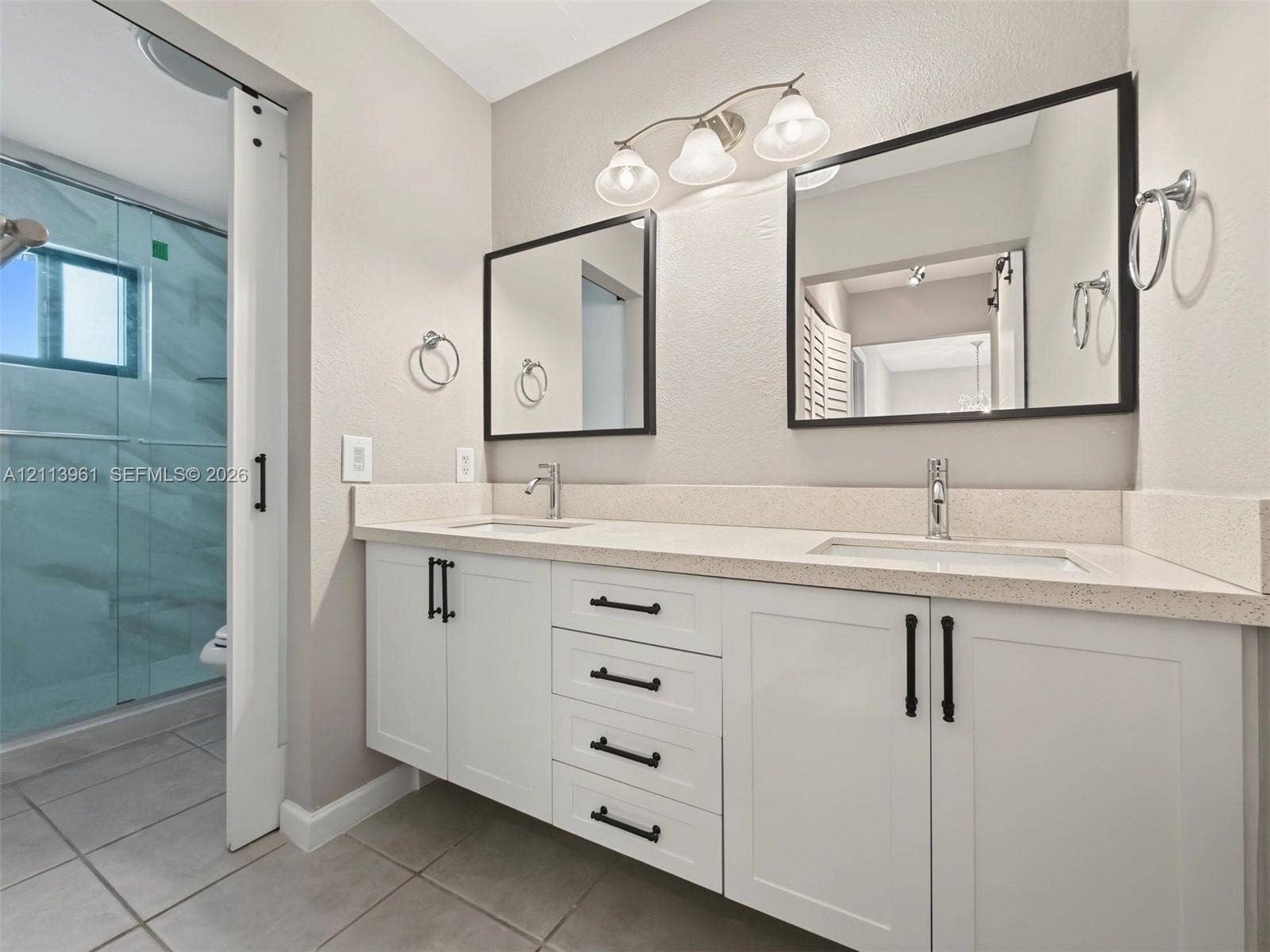 339 City View Drive, #339, Fort Lauderdale, Fort Lauderdale, FL 33311 Dual-sink vanity with white shaker-style cabinetry, quartz countertops, matte black hardware, and two framed mirrors