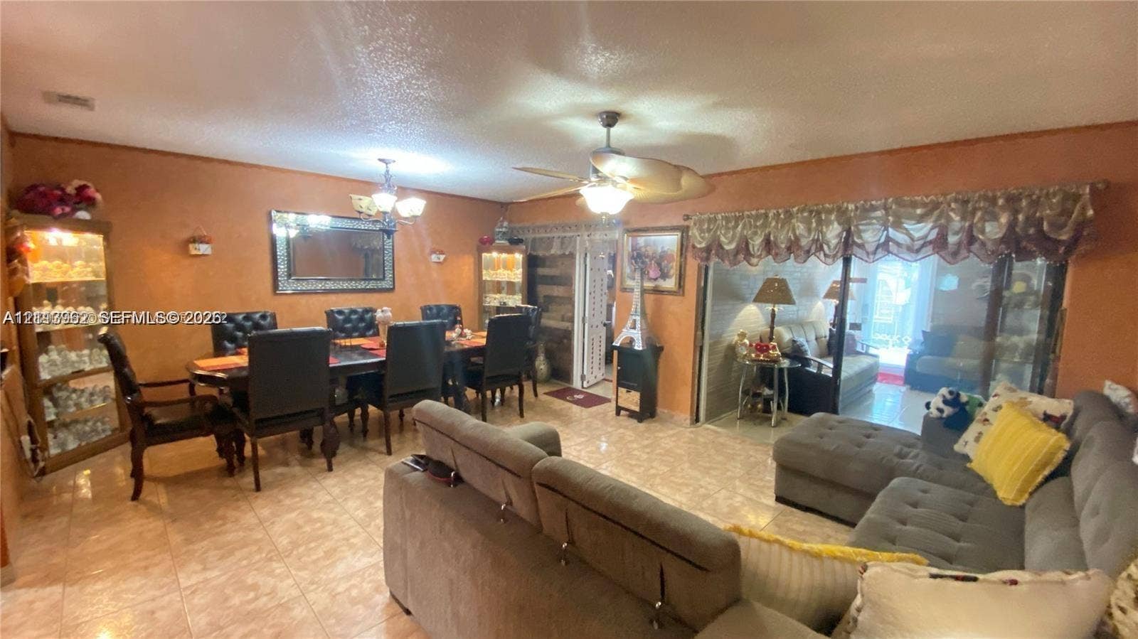 19764 NW 54 Avenue, Miami Gardens, FL 33055 Open-concept interior featuring light-toned tile flooring, recessed lighting, dual ceiling fans, and sliding glass doors with overhead valance trim
