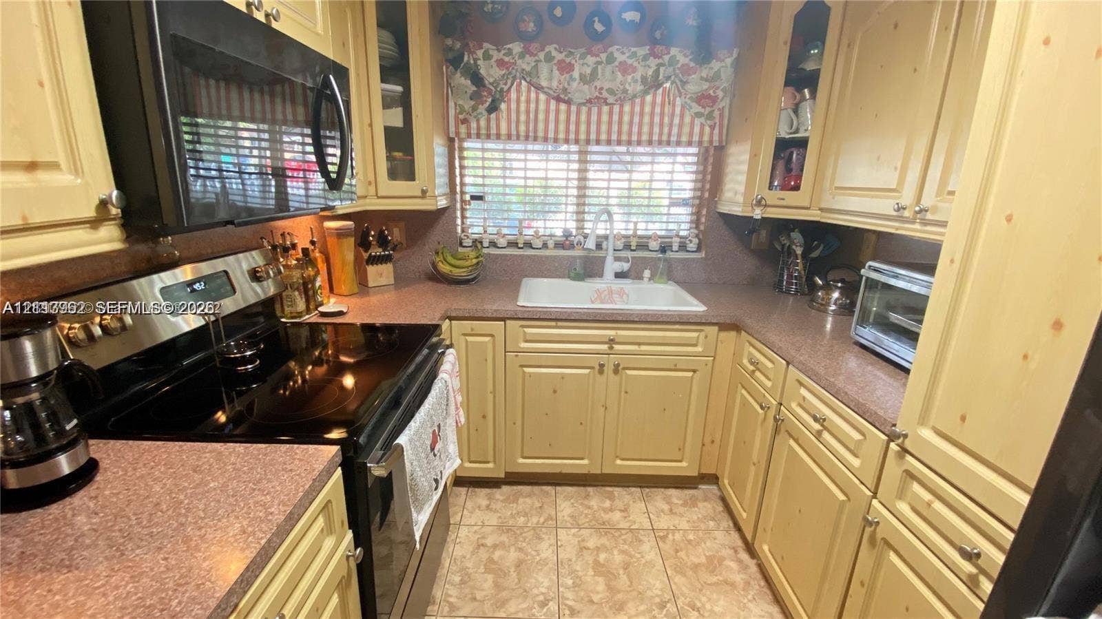 19764 NW 54 Avenue, Miami Gardens, FL 33055 Kitchen featuring custom cabinetry, solid surface countertops, integrated double-basin sink, and ceramic tile flooring