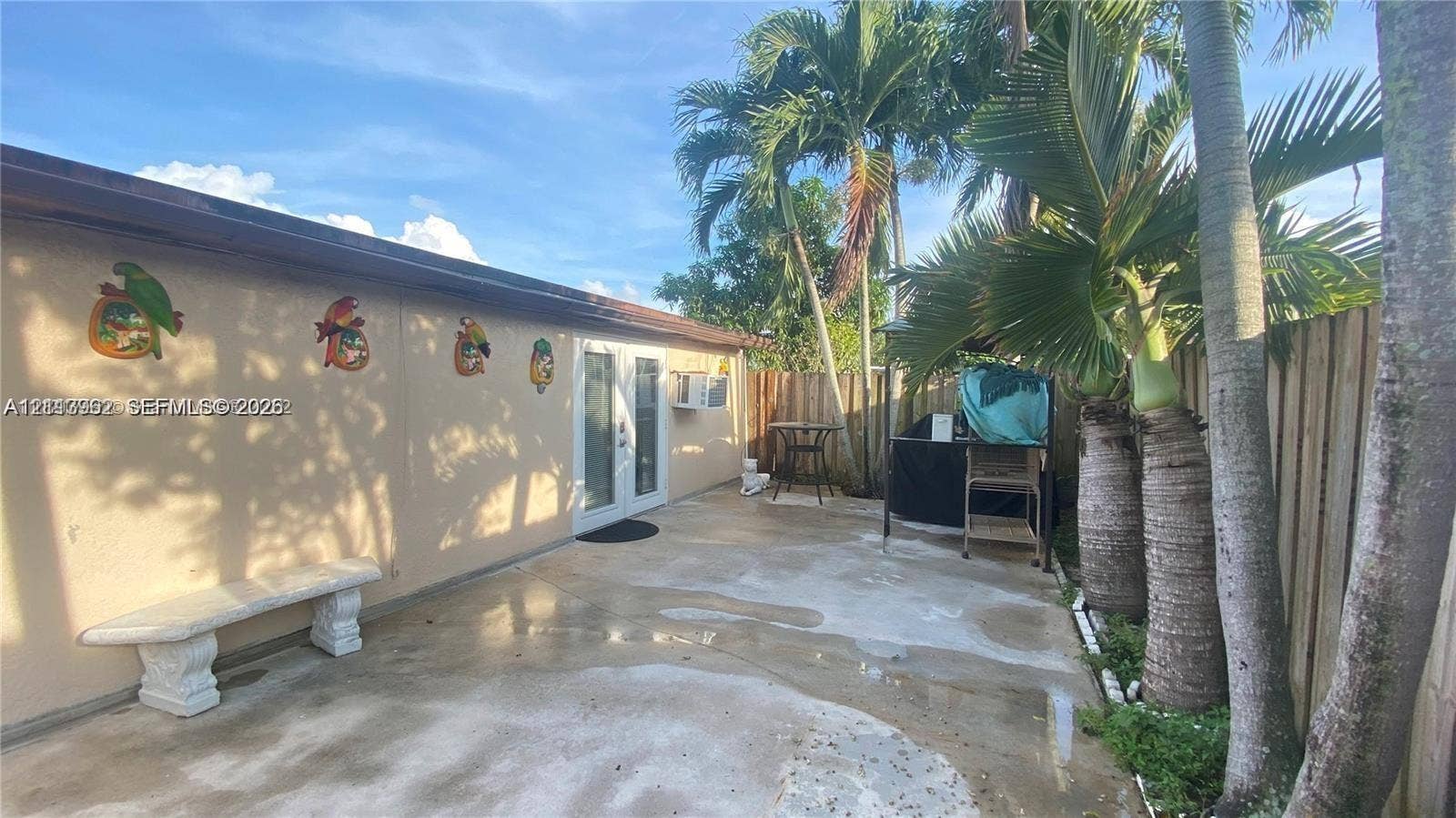 19764 NW 54 Avenue, Miami Gardens, FL 33055 Concrete patio area enclosed by a wood privacy fence and featuring integrated palm trees