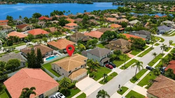 Aerial perspective showcasing a residential property with a tiled roof, multi-car garage, concrete driveway, and a private swimming pool enclosed by privacy fencing