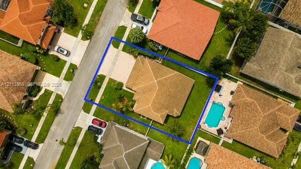Aerial perspective of property featuring a multi-pitched shingle roof, concrete driveway, and expansive corner lot with mature landscaping