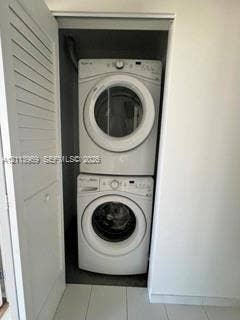 151 SE 1st Street, #1702, Miami, FL 33131 Stacked laundry center featuring a white front-load washing machine, white front-load dryer, and louvered closet door