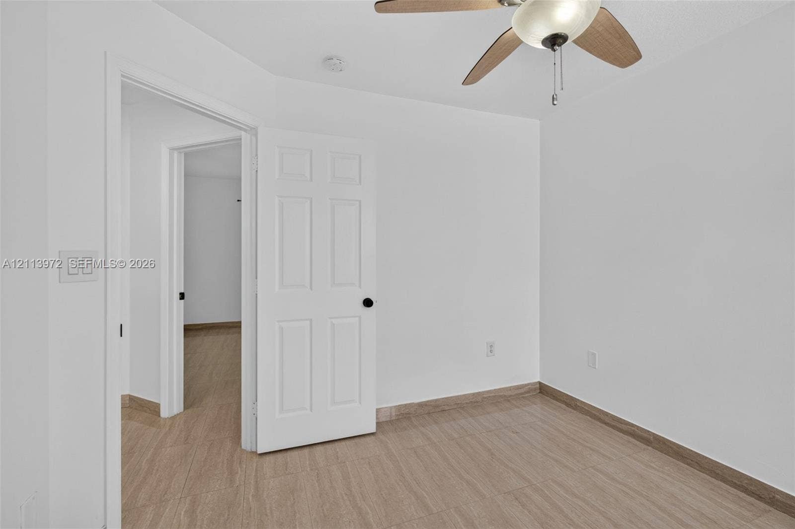 Neutral interior featuring wood-finish flooring, white walls, and a ceiling-mounted light fixture with a fan