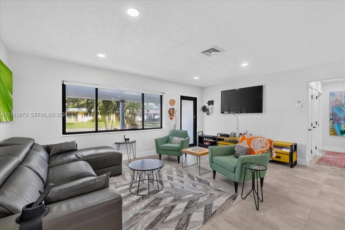 Living area featuring large format tile flooring, recessed lighting, and a picture window