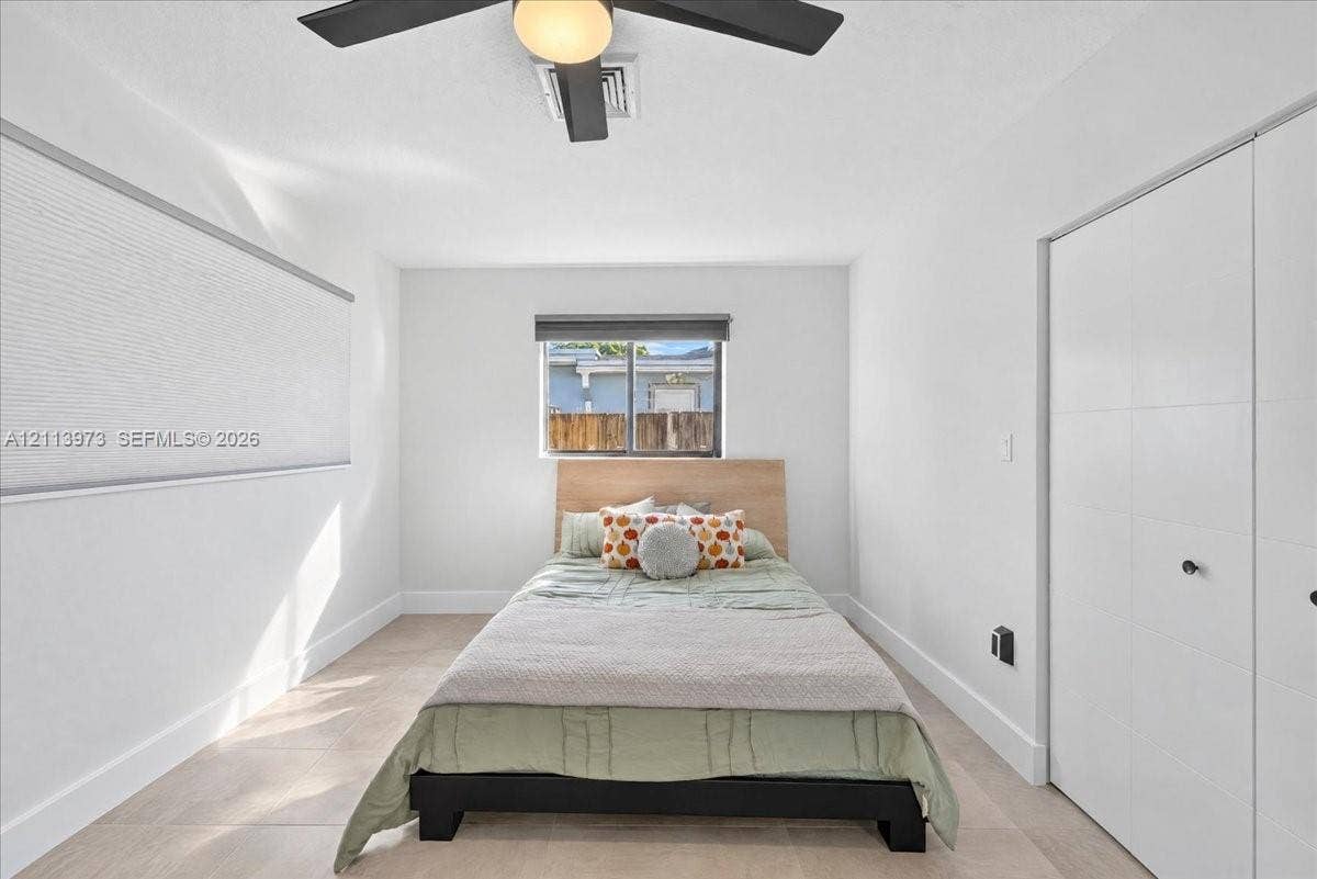 Neutral-toned tile flooring, white interior walls, ceiling fan with integrated lighting, and white multi-panel closet doors