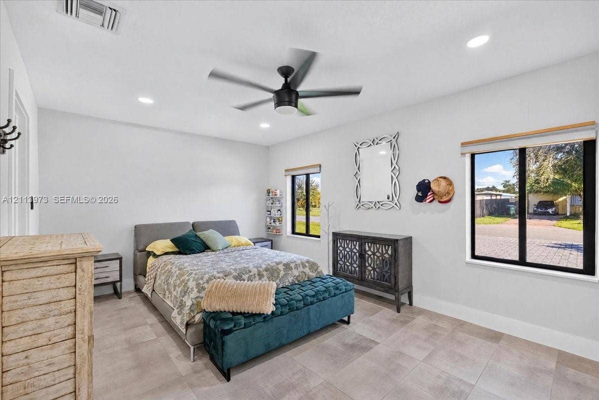 Neutral interior featuring light tile flooring, recessed lighting, a modern matte black ceiling fan, and large windows with black frames