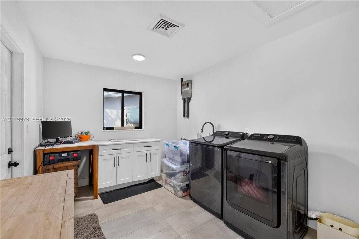 Laundry area featuring white shaker-style cabinetry, a rectangular window with a dark frame, and light-toned tile flooring